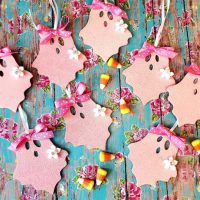Pink glitter wooden ghost Halloween ornaments with polka dot bows and white flowers, sold as a set of eight.