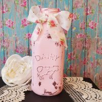 One-of-a-kind pink distressed glass milk bottle with raised dairy cow design and floral bow for coquette shabby chic kitchen decor