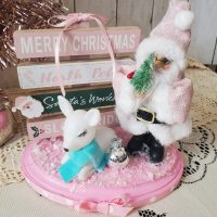 One-of-a-kind pink Santa Christmas diorama with retro reindeer, wooden North Pole sign and faux snow on a pink base