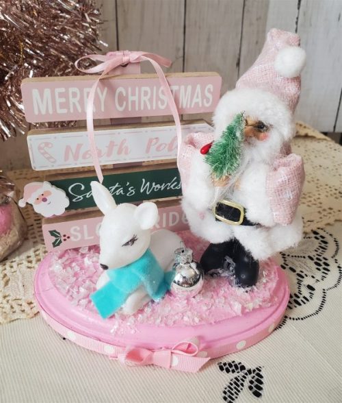 One-of-a-kind pink Santa Christmas diorama with retro reindeer, wooden North Pole sign and faux snow on a pink base