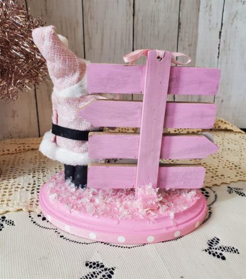 One-of-a-kind pink Santa Christmas diorama with retro reindeer, wooden North Pole sign and faux snow on a pink base back