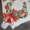 Vintage Christmas tablecloth measuring 52 x 42 inches, featuring red poinsettias, holly, candles, bells, ornaments, and decorative evergreen garlands on a white background.
