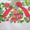 Close-up of vintage Christmas tablecloth showing holly, ornaments, bells, ribbon, and candy cane pattern.