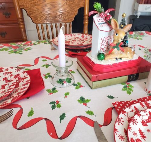 Vintage mid-century holiday table linen displayed on a dining table with classic red and green Christmas print.