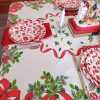 Vintage mid-century Christmas tablecloth with holly, red ribbon, candy canes, bells, ornaments, and greenery.